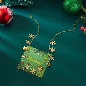 Close-up of golden Christmas necklace with snowflake pendants on a festive green background