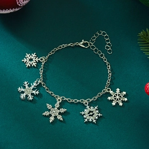 Detail view of silver snowflake charm bracelet with sparkling rhinestones on green background