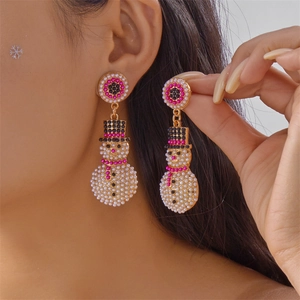 Détail de boucles d'oreilles bonhomme de neige en perles et strass portées par un mannequin