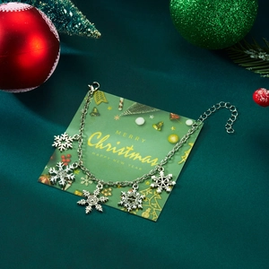 Silver snowflake bracelet with five charms and crystals on a festive green display card