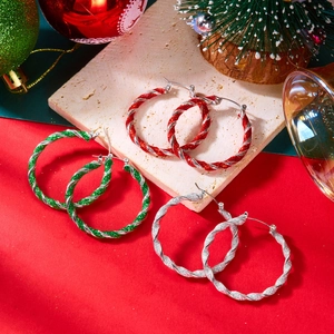 Dettaglio di tre paia di orecchini a cerchio intrecciati a tema natalizio con glitter