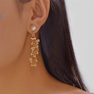 Détail de boucles d'oreilles bonhomme de pain d'épice de Noël avec perle portées par un mannequin