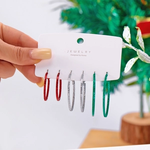 Dettaglio di tre paia di orecchini a cerchio glitterati natalizi in rosso, argento e verde