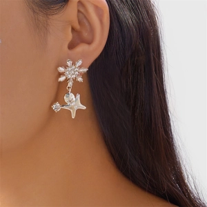 Gros plan de boucles d'oreilles flocon et étoile avec strass sur un mannequin
