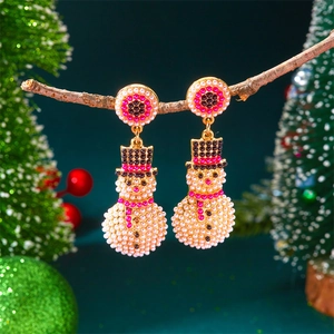 Gros plan de boucles d'oreilles bonhomme de neige de Noël avec perles et strass roses