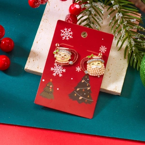 Vue détaillée de boucles d'oreilles Père Noël avec perles sur un fond de fête élégant
