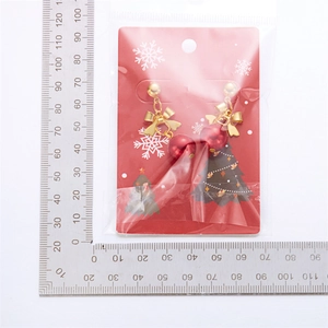 Detailed view of Christmas bell tassel earrings with dimensions on a red card