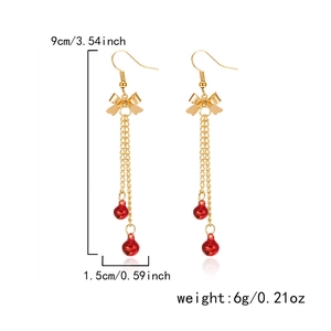 Detail view of long Christmas bell earrings with gold bows and red tassels