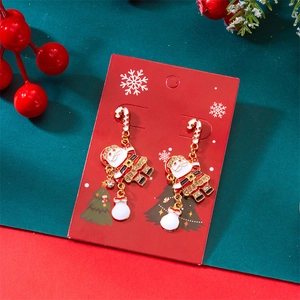 Détail de boucles d'oreilles Père Noël avec cannes de bonbon et strass sur carte de fête
