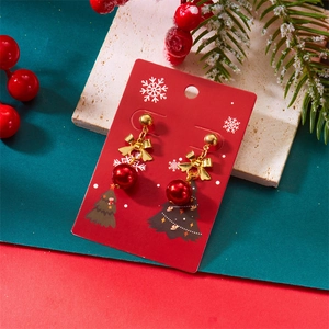 Detail of festive red bead earrings with gold bows on snowflake patterned card