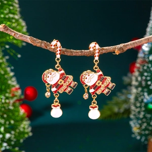 Détails des boucles d'oreilles Père Noël accrochées sur une branche de sapin festive