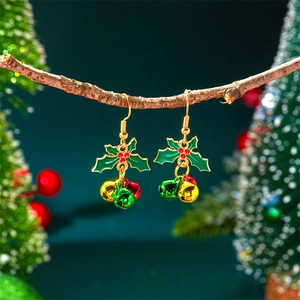 Macro detail of Christmas holly leaf earrings with colorful mini bells on a wooden branch