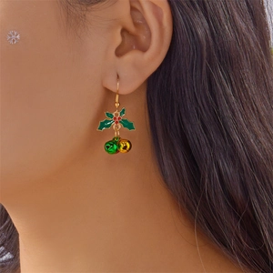 Close-up of Christmas bell earrings with green holly leaves and red berries on a model