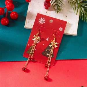 Detail of Christmas earrings featuring gold bows, long tassels and festive red bells