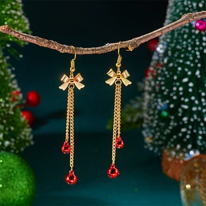 Detailed close-up of festive Christmas tassel earrings with golden bows and red bells