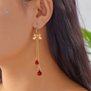 Close-up of Christmas bow earrings with gold chains and red bells on model