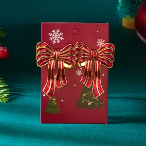 Detail van rode kerststrik oorbellen met gouden glitters op een groene fluwelen achtergrond
