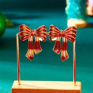 Detail van rode glitter strik oorbellen op gouden standaard met groene achtergrond