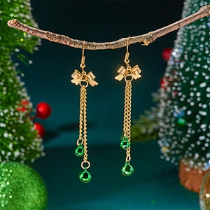 Detail of Christmas tassel earrings with golden bows and vibrant green bells on a branch