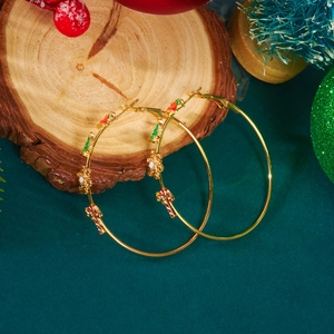 Detail van gouden oorringen met kerstboom en sneeuwvlok hangers in kerstsfeer
