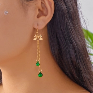 Detail of Christmas bow earrings with gold tassels and green bells on model side view