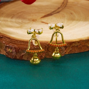 Detail van gouden strikoorbellen met bellen en zirkonia op houten basis