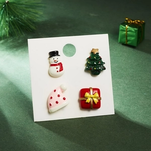 Macro detail of Christmas stud earrings set featuring a snowman, tree, hat, and gift box