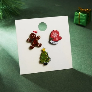 Macro view of Christmas acrylic brooches featuring gingerbread man and tree on card