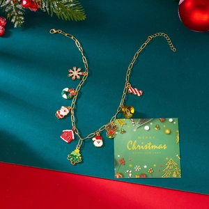 Detail van de kerst-emaille bedeltjes aan een gouden ketting met Kerstman en boompjes