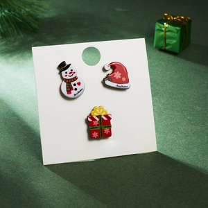 Detailed view of three acrylic Christmas brooches with snowman and Santa hat on display card