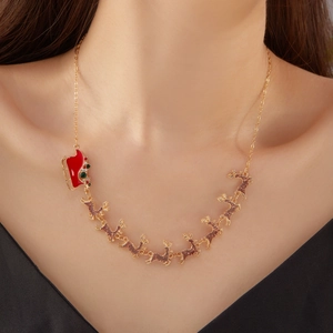 Détail d'un collier de Noël doré avec traîneau en émail rouge et pendentifs renne
