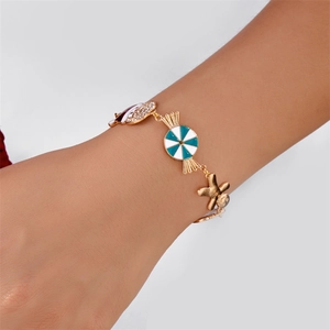 Bracciale di Natale dorato con ciondoli a forma di pan di zenzero e caramelle blu al polso