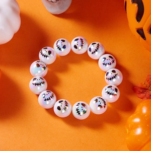 Dettaglio del bracciale con perline di Halloween e stampe di fantasmi su sfondo arancione