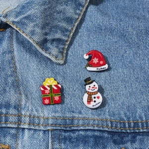 Three-piece Christmas enamel pin set with snowman and Santa hat on denim jacket