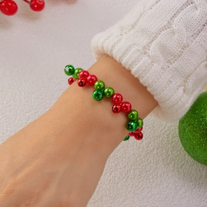 Dettaglio del bracciale natalizio con campanelli rossi e verdi su un polso