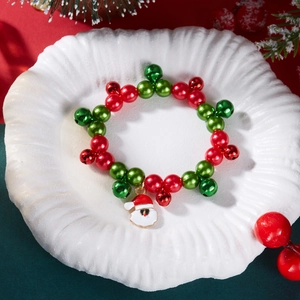 Dettaglio del bracciale natalizio con perline rosse verdi e ciondolo di Babbo Natale