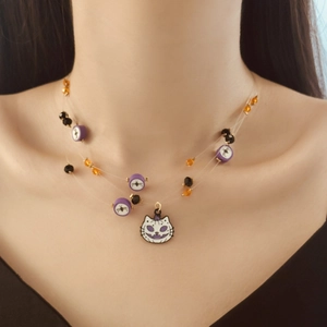 Detail of layered Halloween necklace with cat pendant and purple spider pattern beads