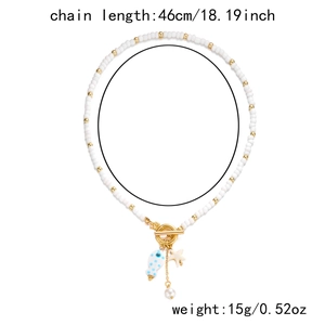 Detail of beaded necklace with blue fish pendant and golden OT toggle clasp