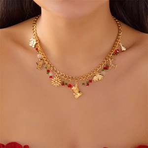 Detail van gouden kerstketting met hangers van boom, sneeuwvlok en hert op cubaanse ketting