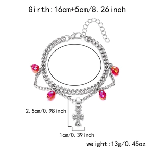 Détail du bracelet double chaîne argenté orné de perles rouges et d'un pendentif croix