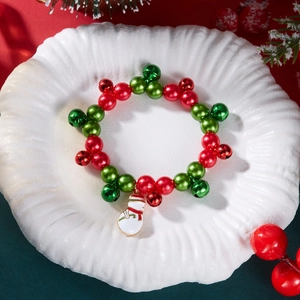 Dettaglio del bracciale natalizio con perline, campanelli e ciondolo a forma di pupazzo di neve