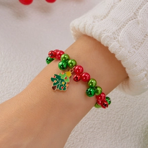 Dettaglio di un bracciale natalizio con campanelli rossi e verdi e ciondolo albero di Natale