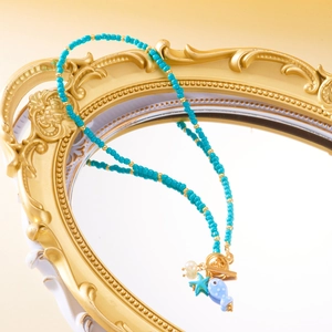 Detail of beaded necklace with ceramic fish, starfish charm, and golden toggle clasp