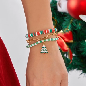 Close-up of three-piece Christmas bracelet set with snowflake and tree charms on a wrist