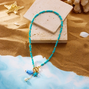 Detail of beaded necklace with blue fish, starfish charms and golden toggle clasp