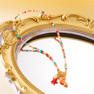 Detail of beaded necklace featuring orange fish and red starfish charms with OT clasp