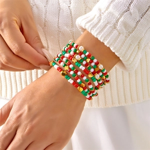 Detailopname van gestapelde kerstkralenarmbanden met sneeuwpop en gouden hartbedels