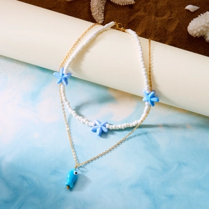 Detail of beaded sea starfish necklace and blue fish pendant over creative ocean scene