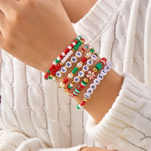 Detail van kerstarmbandset met kralen en de letters Merry en Happy op een winterse trui