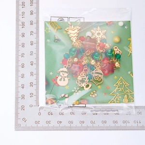 Christmas charm set with colorful beads and festive pendants next to a sizing ruler